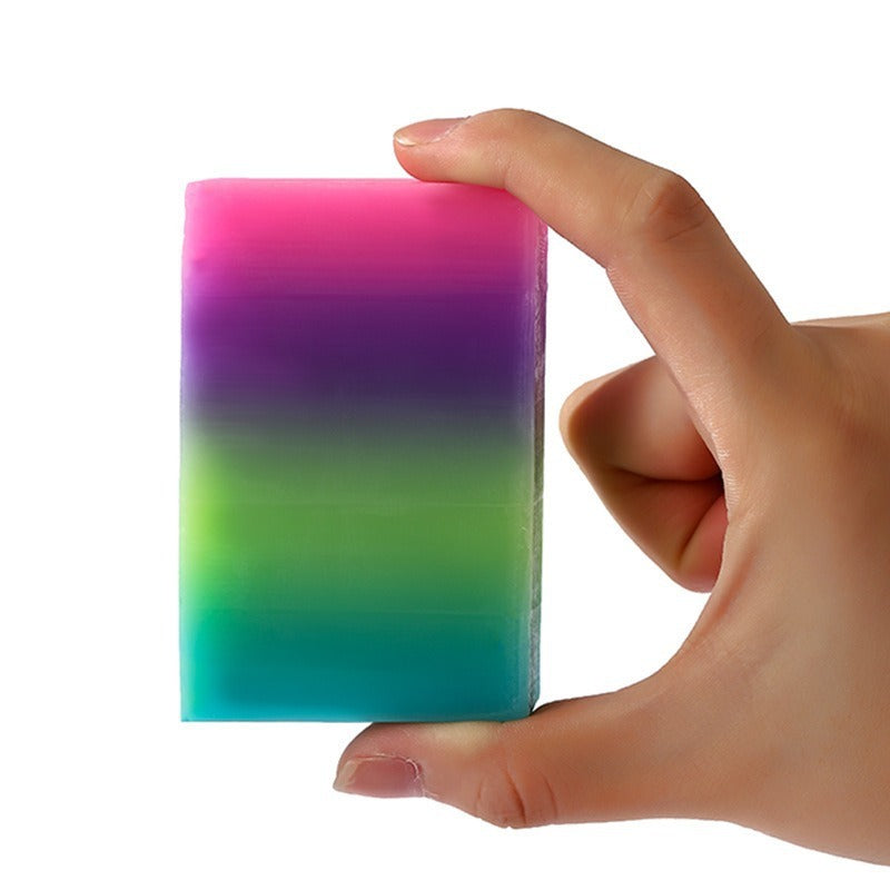 Hand holding a colorful rainbow Oil Bath Soap for Kids by Arts And More with vibrant layers